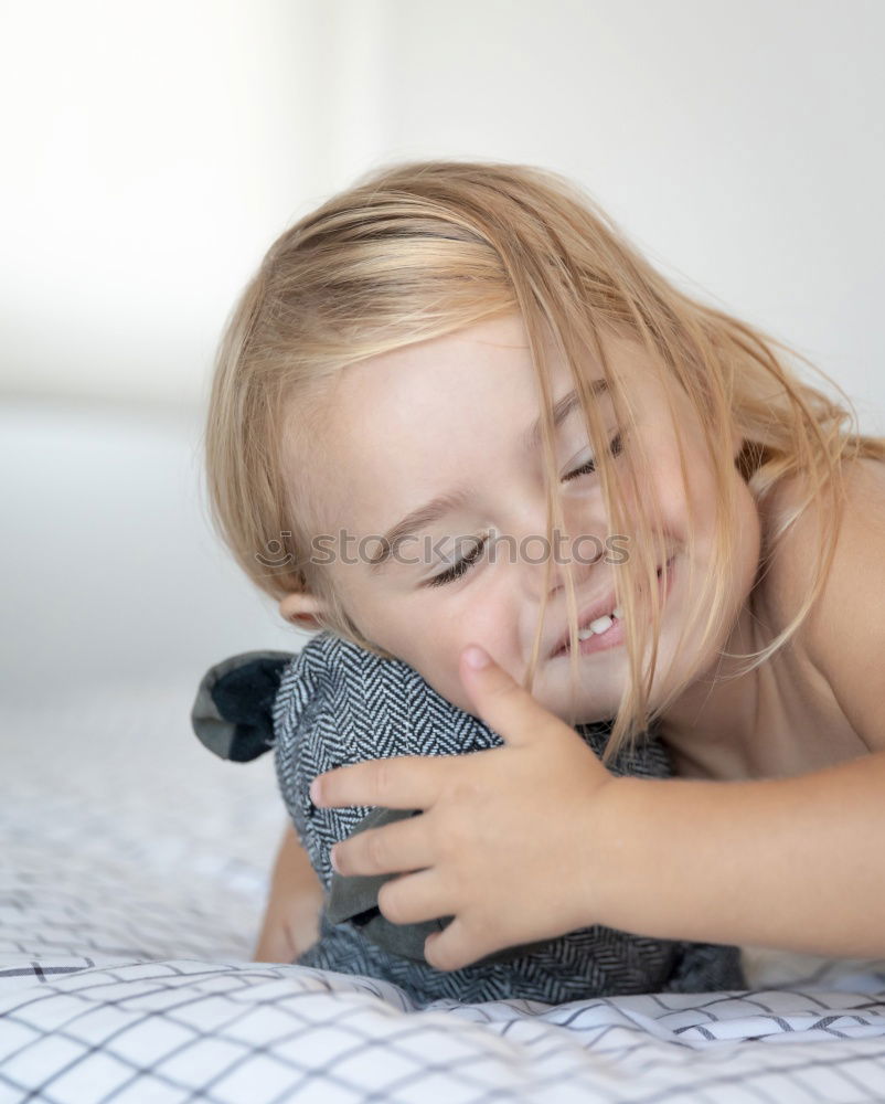 happy little child girl lying on her bed in the morning