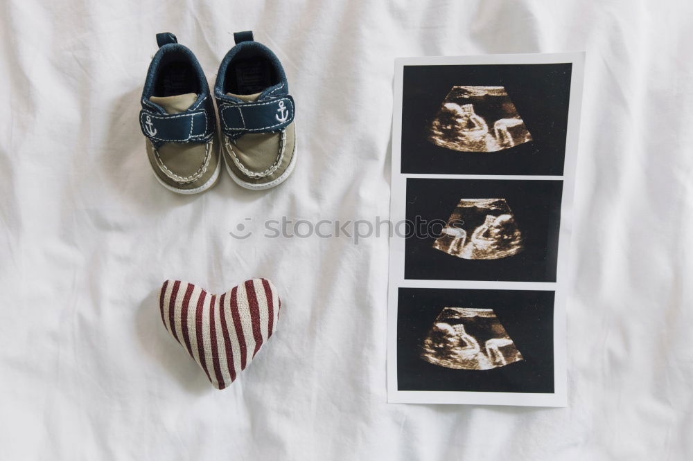 Schwangerschaftstests, Babykleidung und Ultraschalluntersuchung auf dem Bett, Ansicht von oben