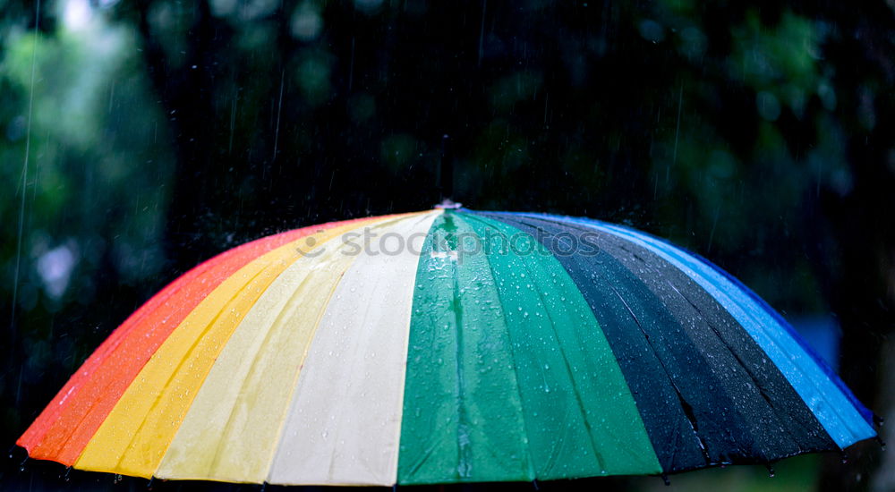 Similar – Rain on umbrella in rainbow colors under heavy rain against background of cloudy sky. Rainy weather concept.