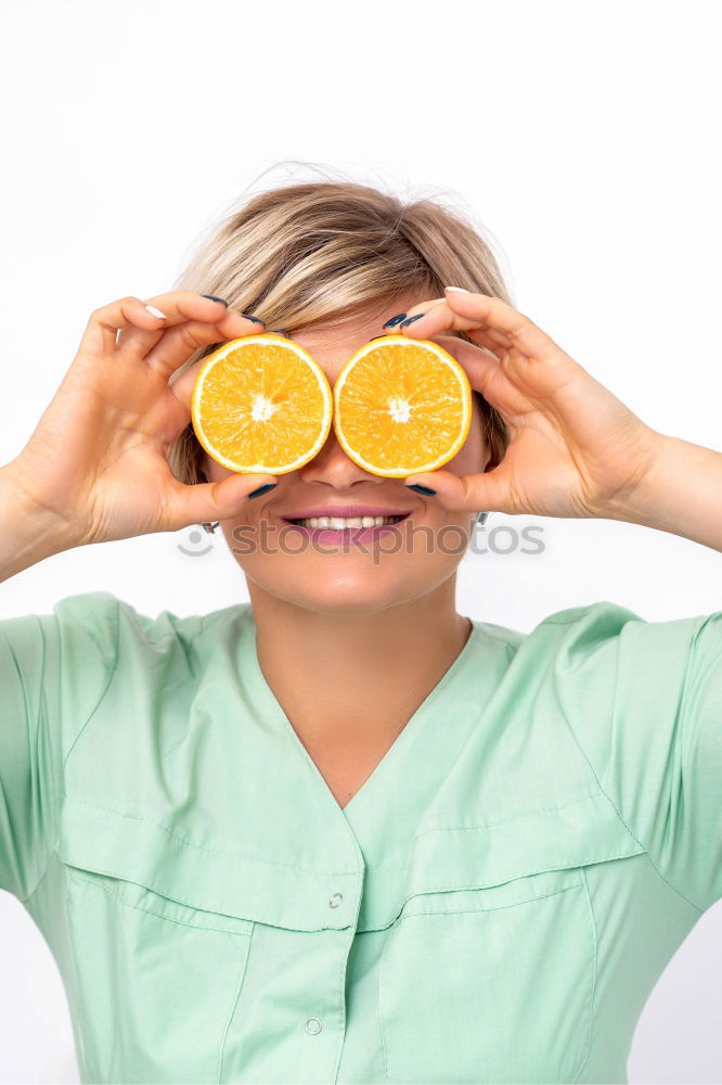 smiling little girl holding oranges over her eyes