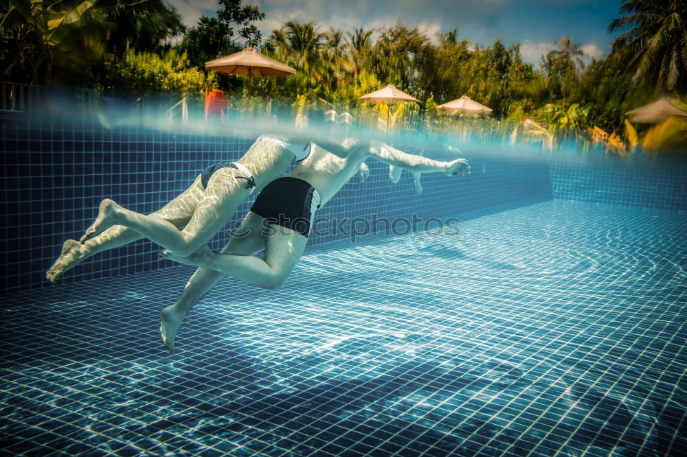 junge Frau im Pool hält ein Glas Weißwein in die Höhe während ihr das Wasser bis zum Hals steht