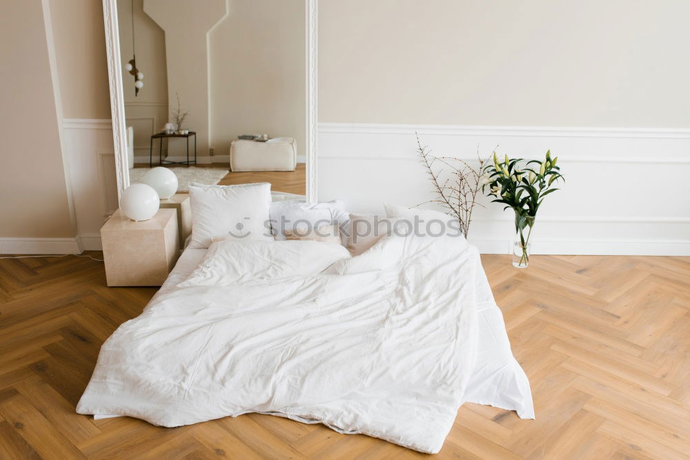 Similar – Ein Doppelbett mit weißer Bettwäsche und beigen Kissen in einem hellen skandinavischen Schlafzimmer, ein Bett auf dem Boden und Blumen in einer Vase