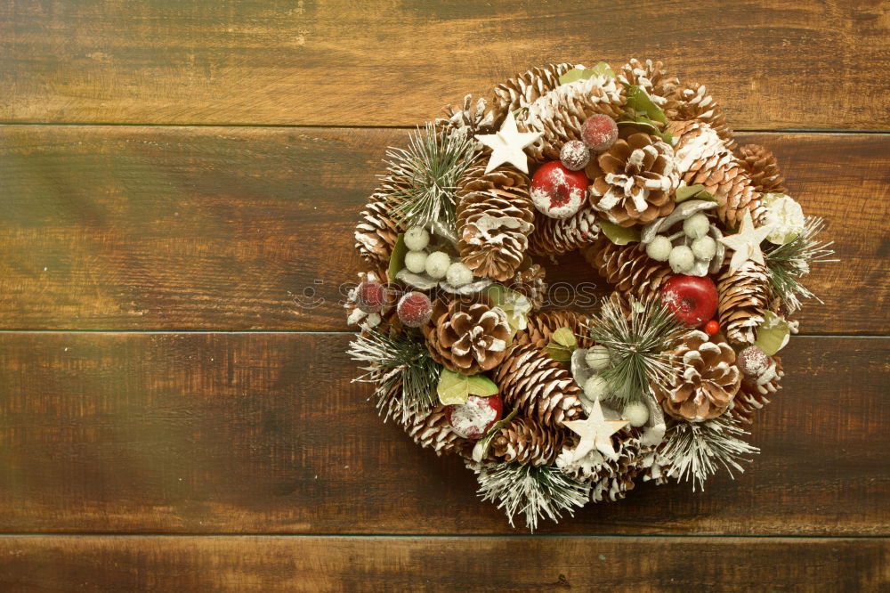 Delicate Christmas wreath of pine cones on wooden background