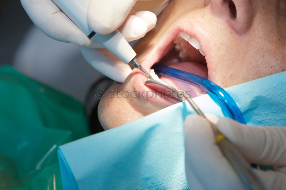 Seated young man is being examined his teeth by a dentist.