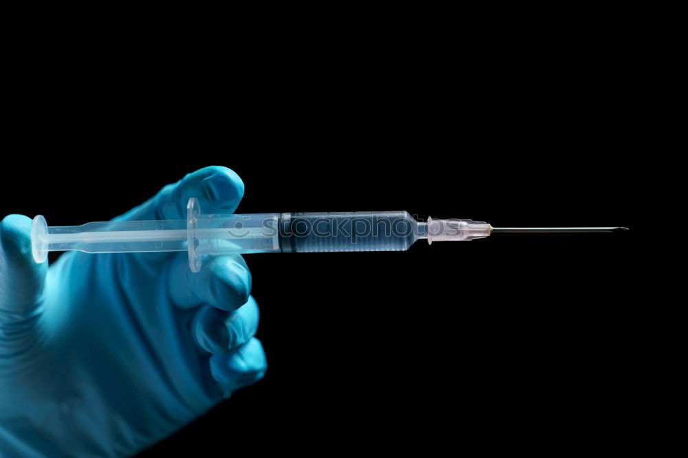 Small bottle of medicine and syringe on blue background