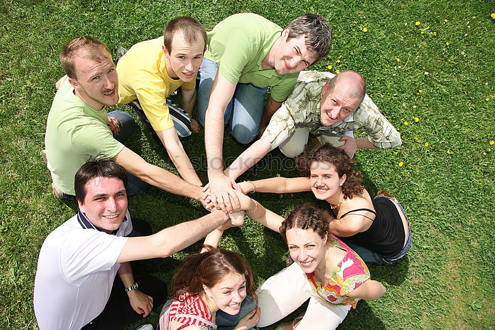 Women and men laying on grass wearing casual clothes.