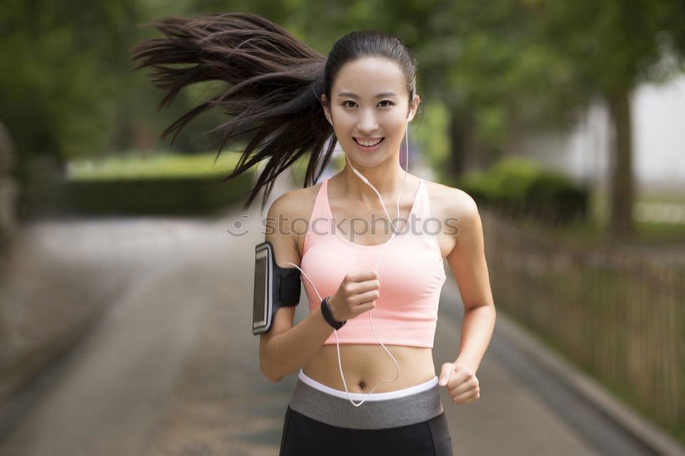 Woman jogging along a country road while listening to music