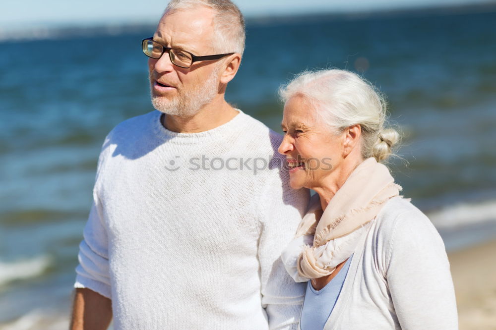 Senior man and woman having a run along the shore. Scene with sea, sand and trees. Healthy and active way of life