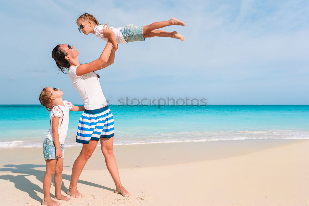 Mother and children playing on the beach at the day time. Concept of friendly family.