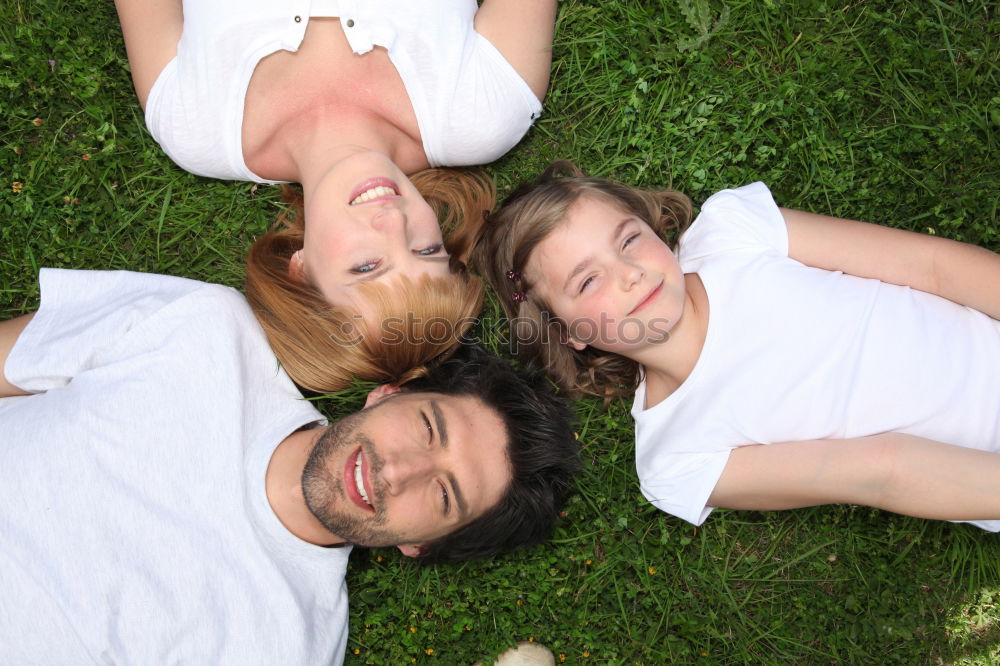 Women and men laying on grass wearing casual clothes.