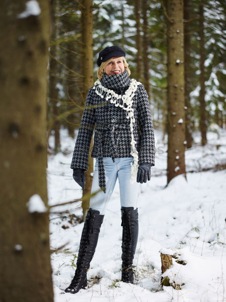 woman leaning against tree in winter landscape