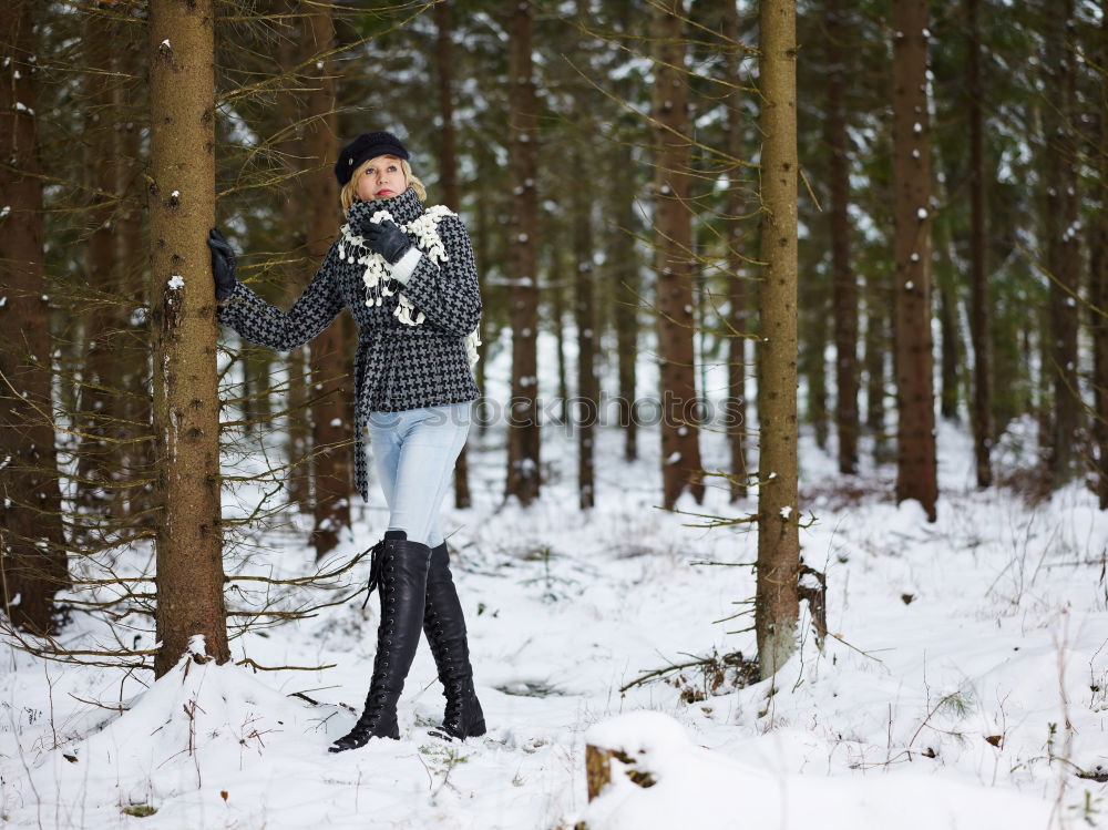 Similar – woman leaning against tree in winter landscape