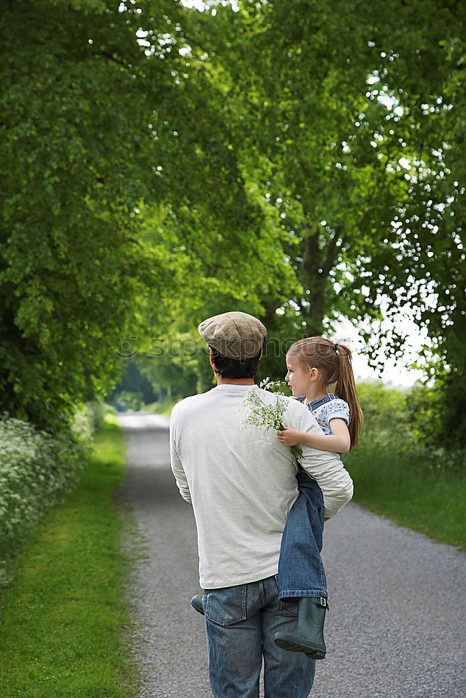 Similar – Back view of senior man holding adorable baby girl in his arms over a nature background