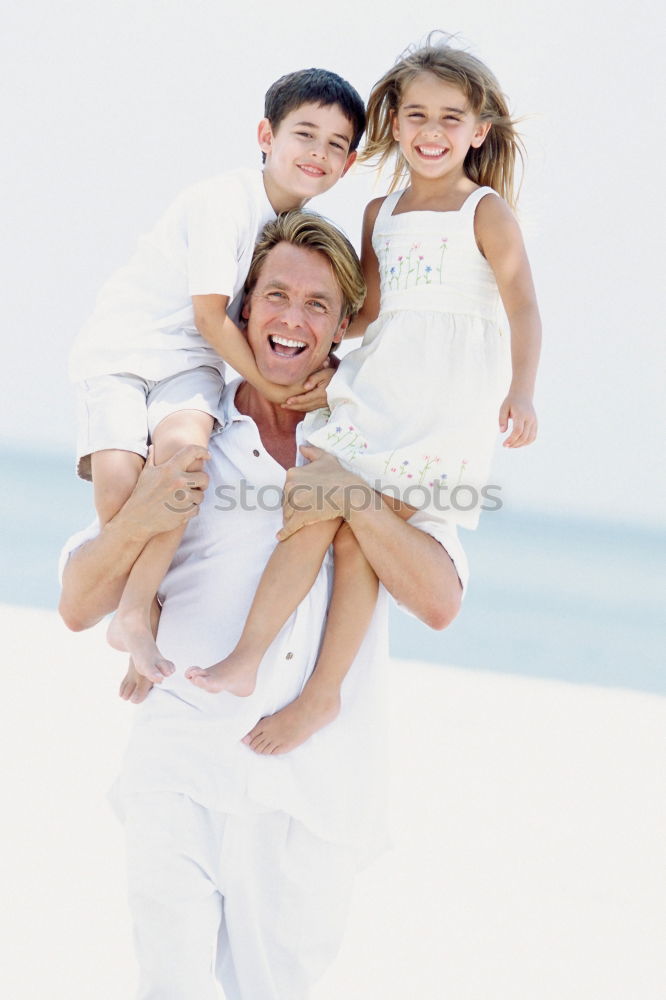 Father and children playing on the beach at the day time. Concept of friendly family.