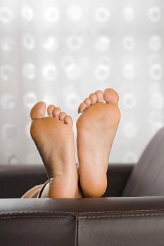 Happy children sitting on the bed barefoot.