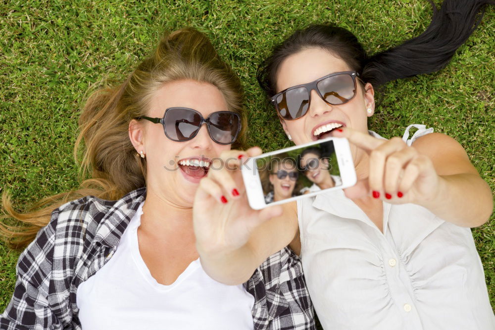 Similar – Two happy teenage girls lying on the grass sharing headphones to listen to music