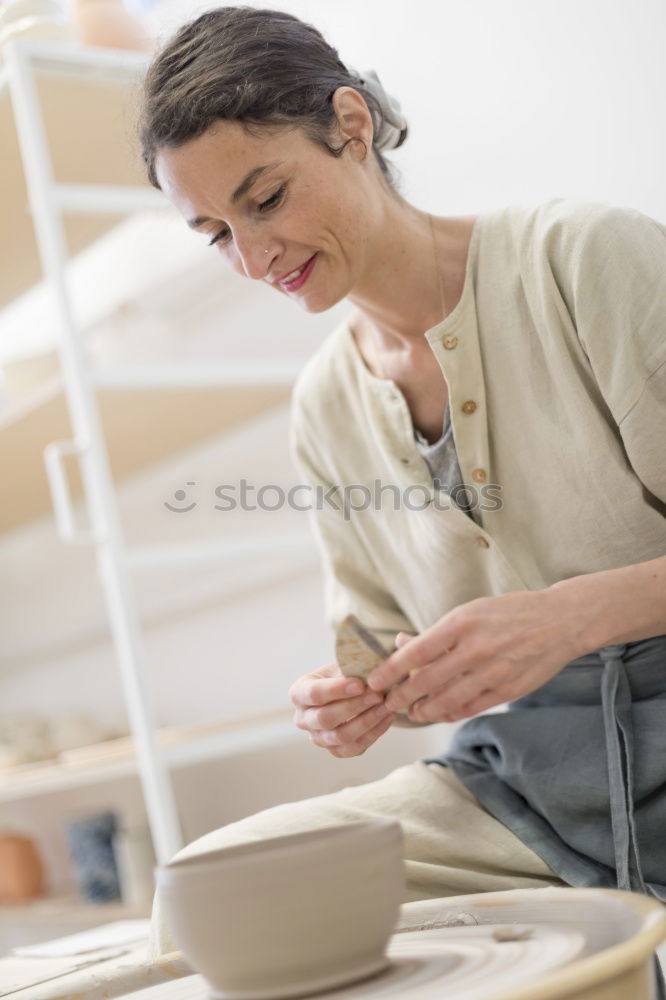 Similar – Image, Stock Photo Young female sitting by table and making clay or ceramic mug in her working studio
