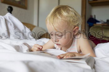 Similar – Image, Stock Photo little boy is lying on the bed and reading a book at the day time