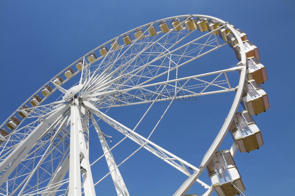 Der Blick hinauf zu einem Riesenrad mit blauem Himmel dahinter.