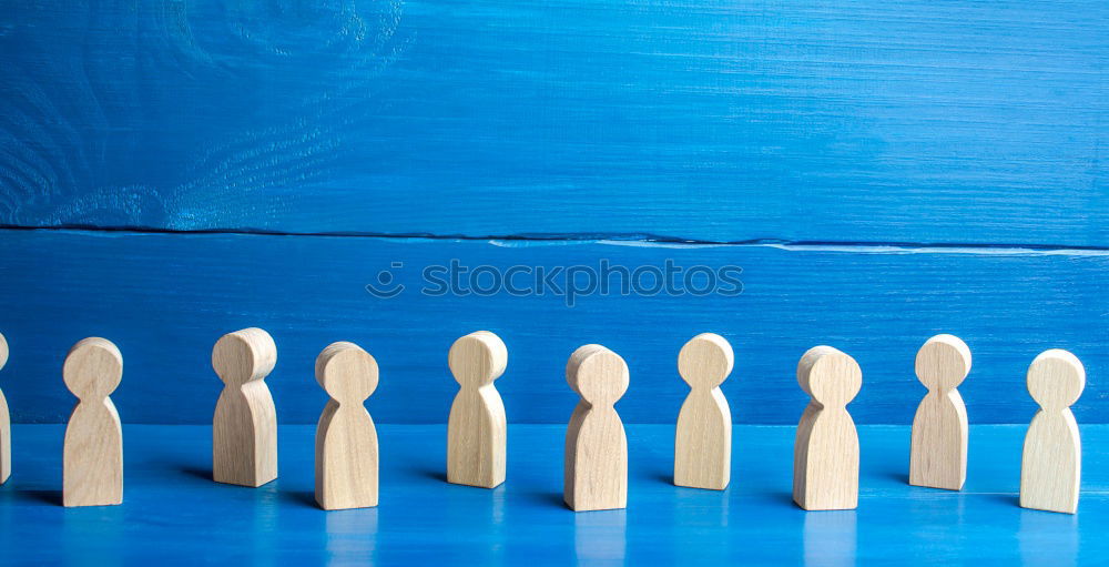 Similar – A red playing figure stands together with white playing figures in a circle on a blue background