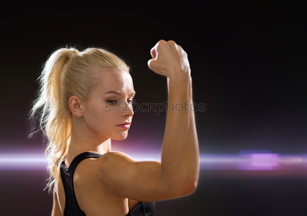 Close up side view profile portrait of one young athletic woman shadow boxing in sportswear in gym over dark background, looking away