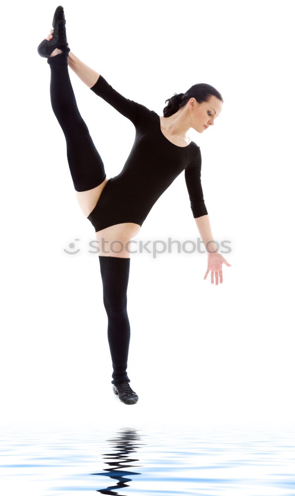 Teen rhythmic gymnast is holding leg in vertical split doing ribbon exercises.