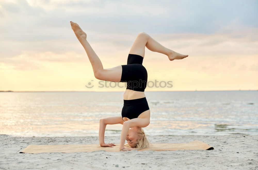 Similar – Agile young woman doing a handstand outdoors in the countryside balancing on her hands with her legs bent in opposite directions