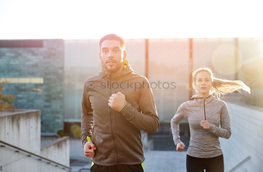 Active young couple jogging side by side in an urban street