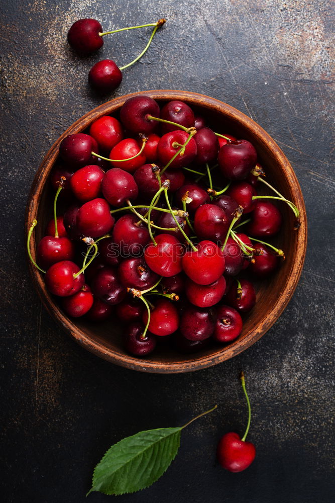 Sweet cherries in a blue bowl on a dark wooden table