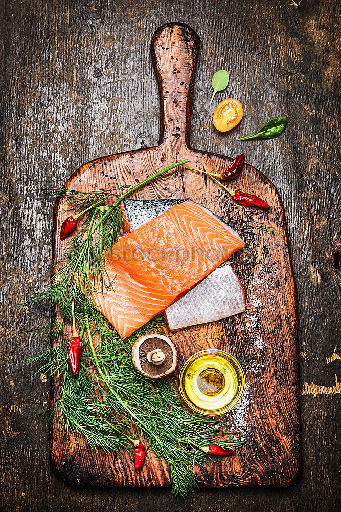 Similar – Salmon fish fillets on chopping board with fresh vegetables