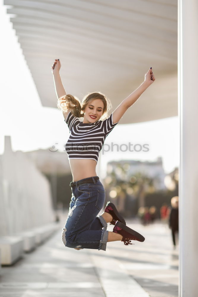 Funny blonde woman jumping in urban background.