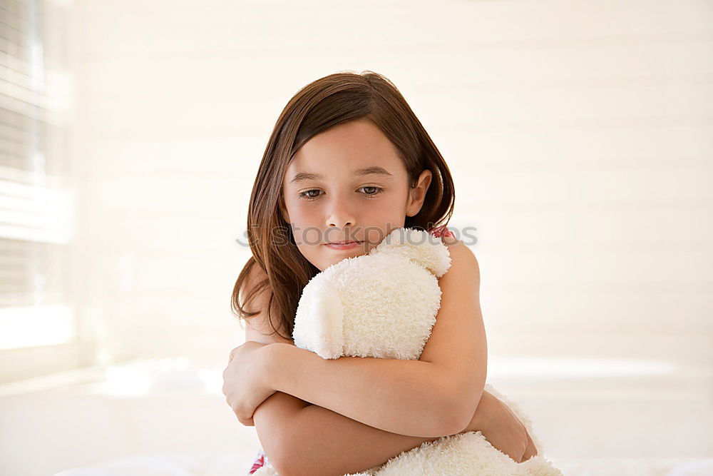 Similar – happy child girl sitting on bed and hugs pillow