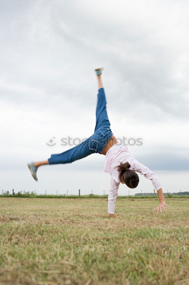 Similar – Agile young woman doing a handstand outdoors in the countryside balancing on her hands with her legs bent in opposite directions