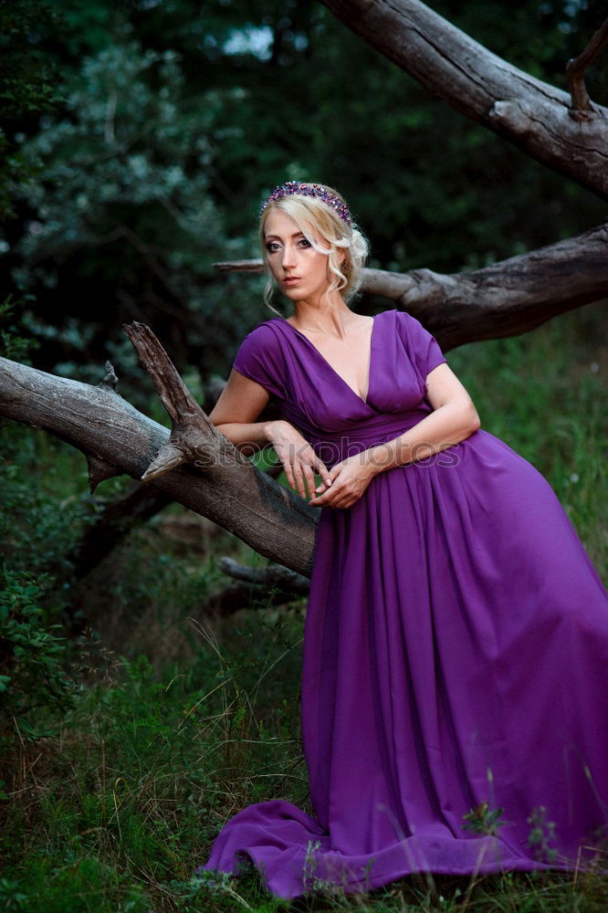 Similar – Young tall woman sitting barefoot by tree in forest in purple wedding dress