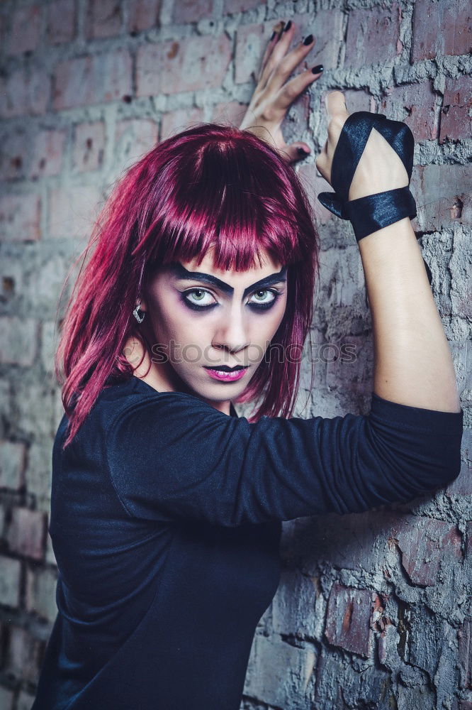 Portrait of an eccentric rocker wearing black clothes. He has tattoos and long purple hair.