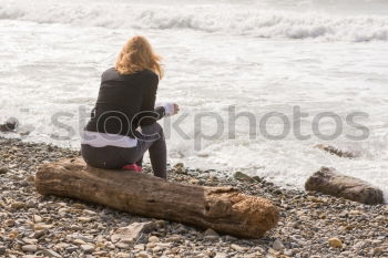 Similar – Rear view of a woman sitting on a wooden bench and looking at a lake