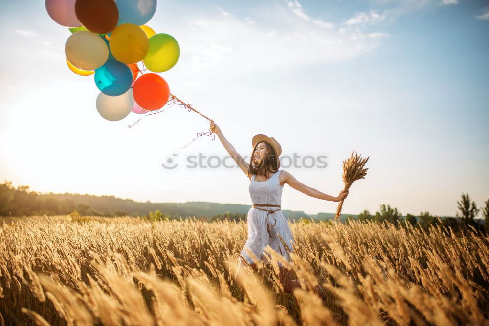 boy running through the field with balloons