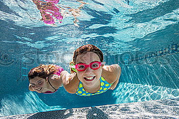 two little girls playing in the pool at the day time