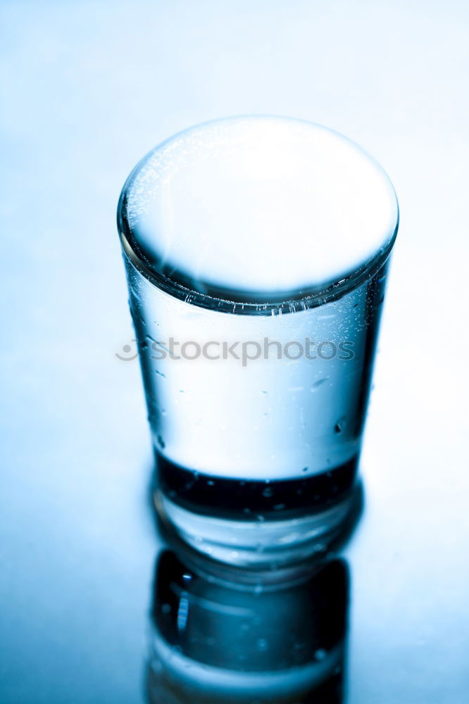 Glass filled to the brim with water in monochrome blue.