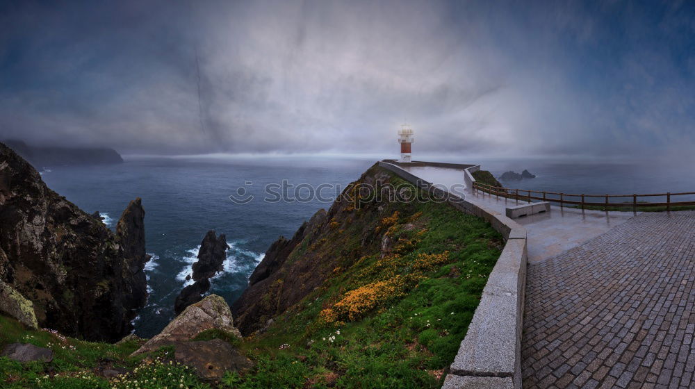 Felsenküste mit Leuchtturm in der Abenddämmerung