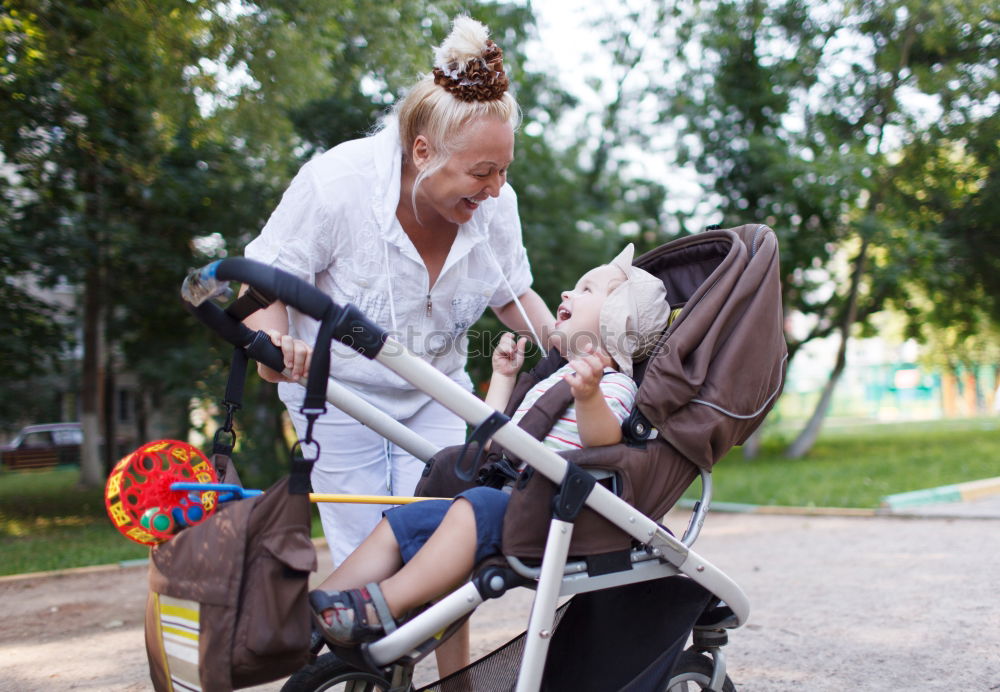 Foto Bild Oma spielt mit ihrem Enkel im Kinderwagen im Garten.