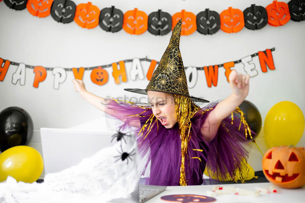 Beautiful girl disguised of witch decorating a pumpkin at home.