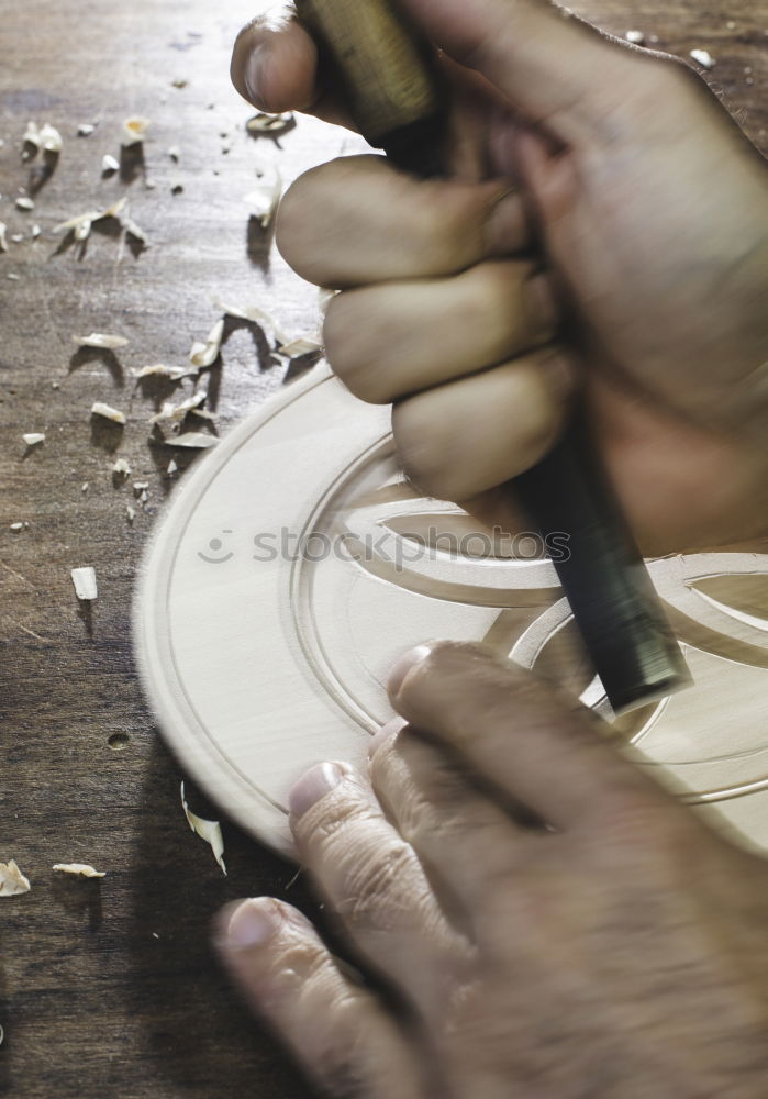 Hands of woodcarver make wooden bowl