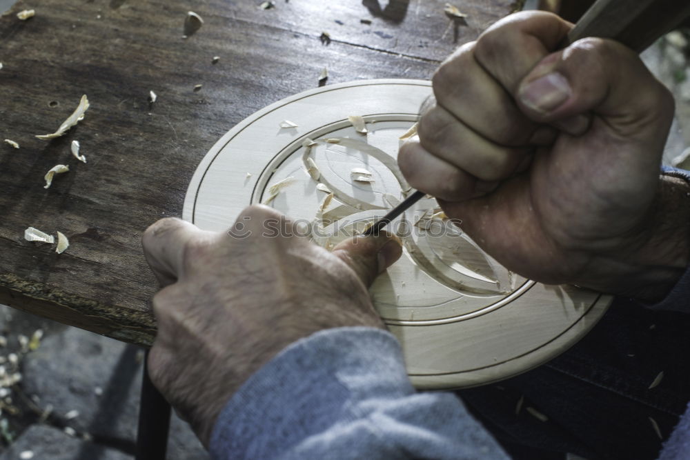 Hands of woodcarver make wooden bowl