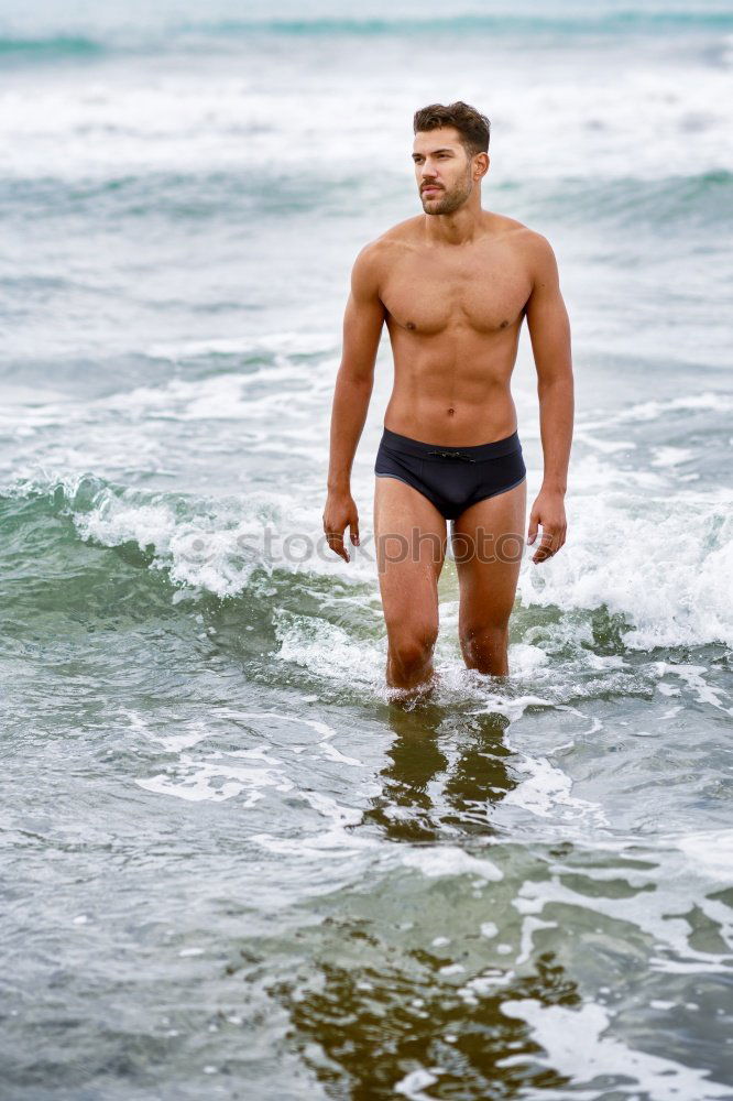 Handsome muscular man bathing on the beach