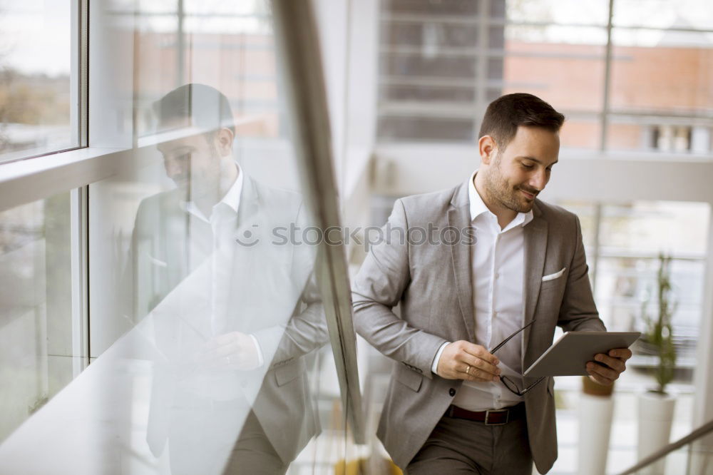 Geschäftsmann mit Blick auf das Smartphone im modernen Firmenbüro.