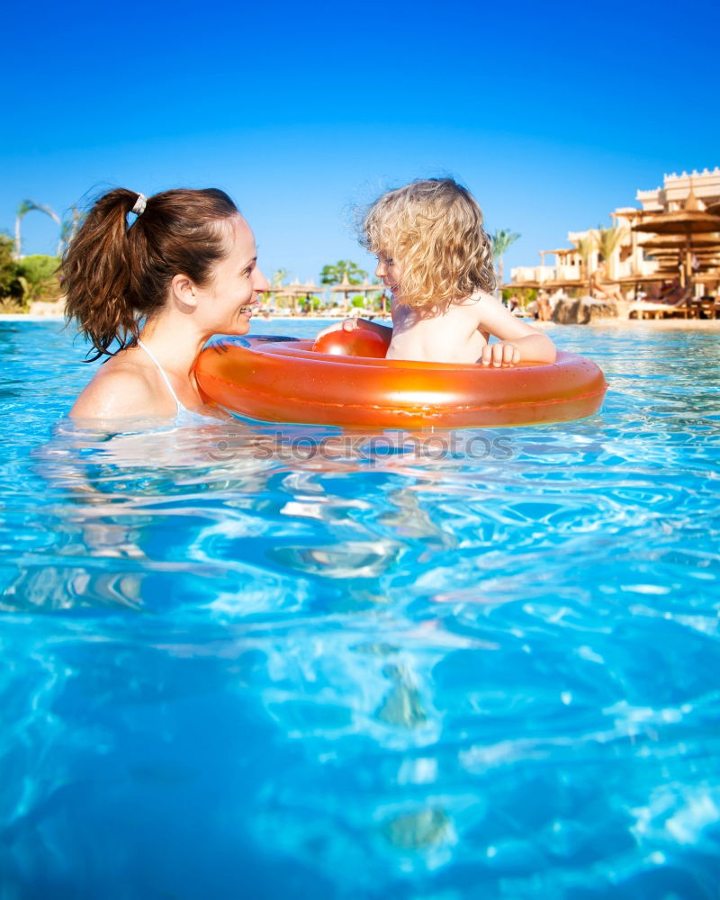 Two funny kids  in the pool on an air mattress