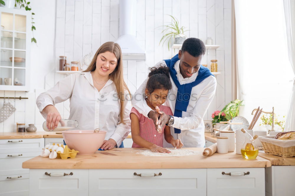 Little sisters cooking with her mother in the kitchen.