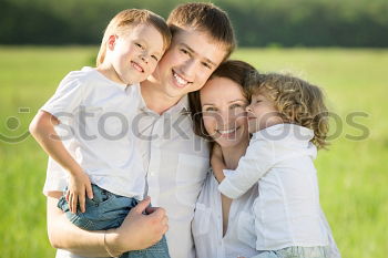 happy family of four hand in hand on the field