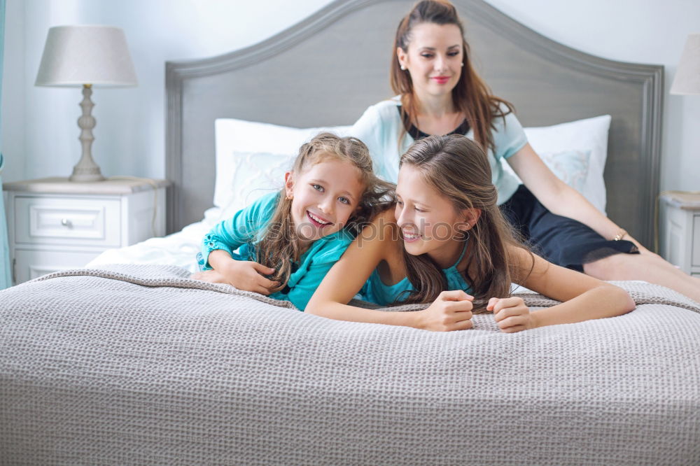 Similar – Three sisters playing with each other lying down in bed at home listening to music